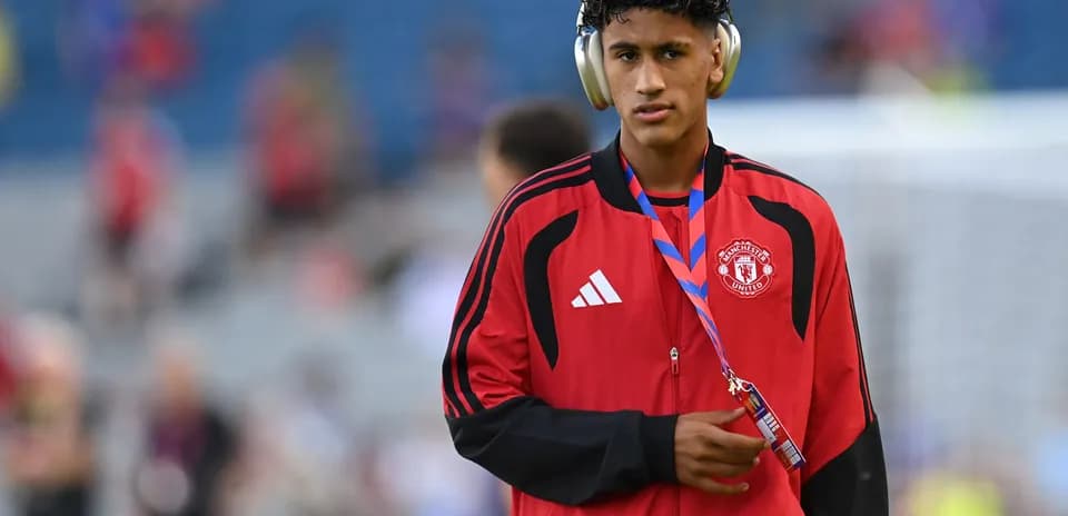 Игрок Manchester United в красной куртке на стадионе