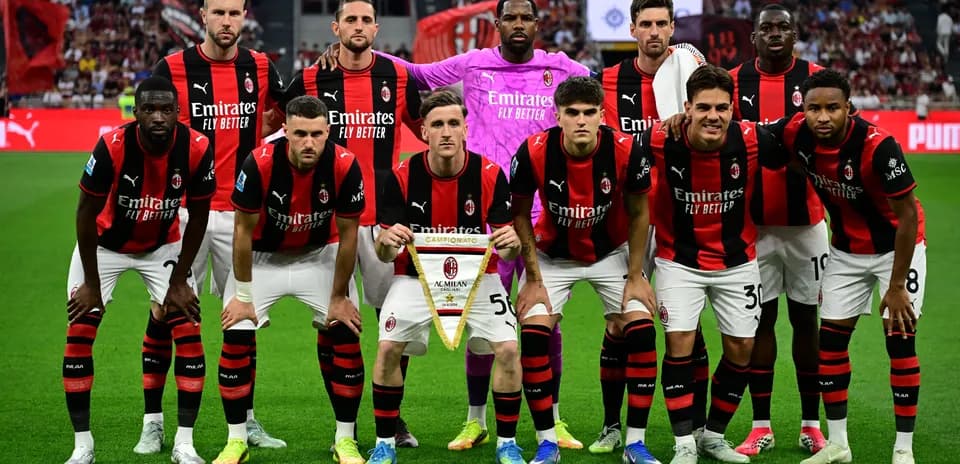 Команда AC Milan позирует с трофеем на поле