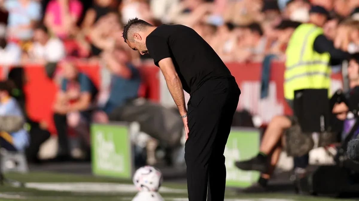 Тренер наклонился над мячом у поля