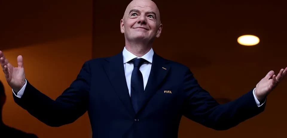 Человек в костюме с логотипом FIFA на трибуне