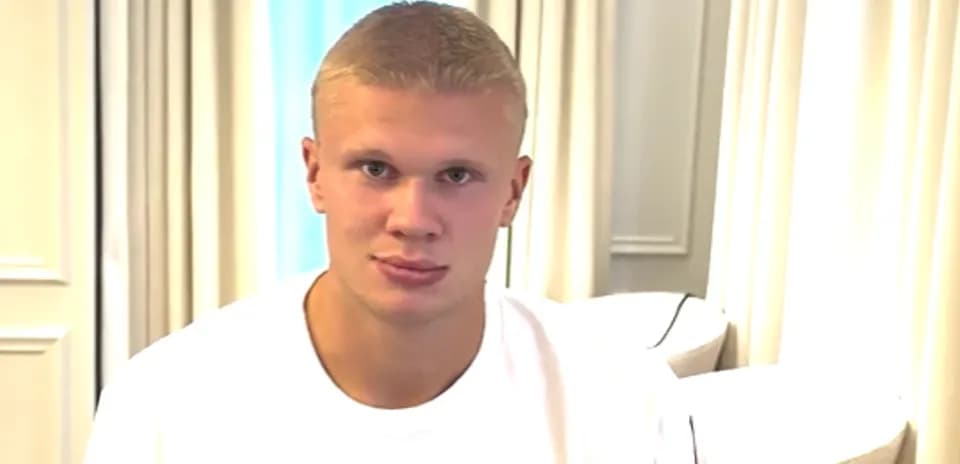Молодой человек в белой футболке сидит на диване