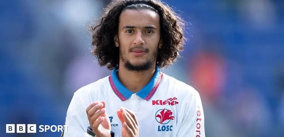 Игрок в белой форме аплодирует на стадионе