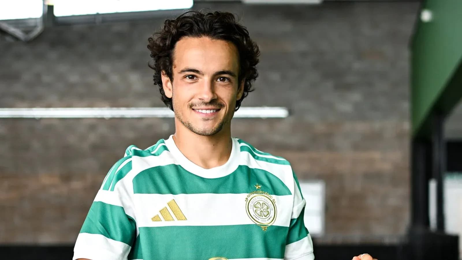 Игрок в зеленой и белой футболке позирует на фоне