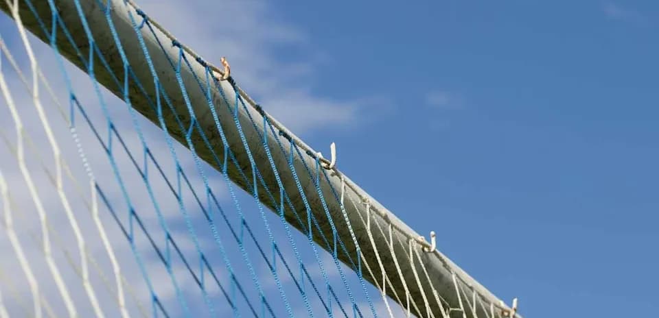 Close-up of goal net against blue sky