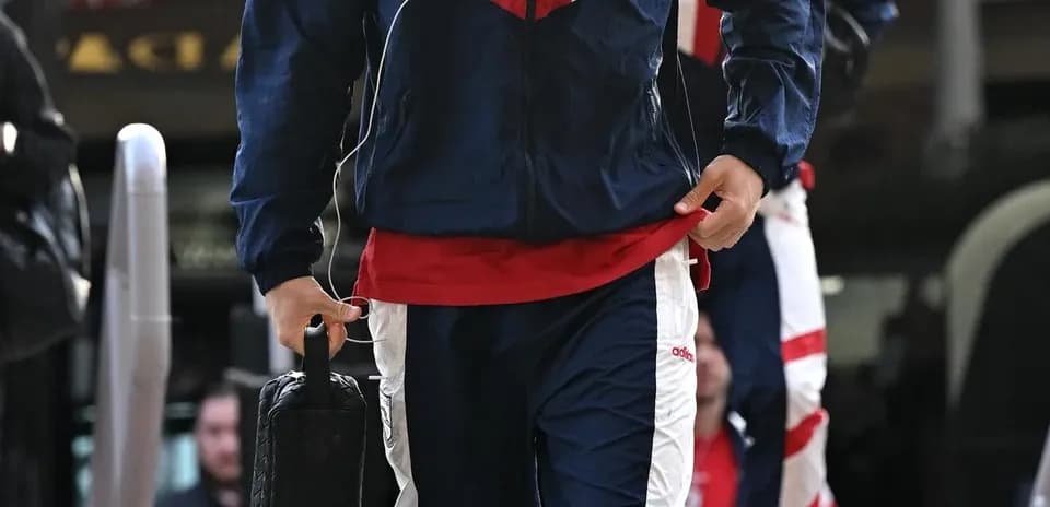 Игрок в спортивной одежде с чемоданом на выходе